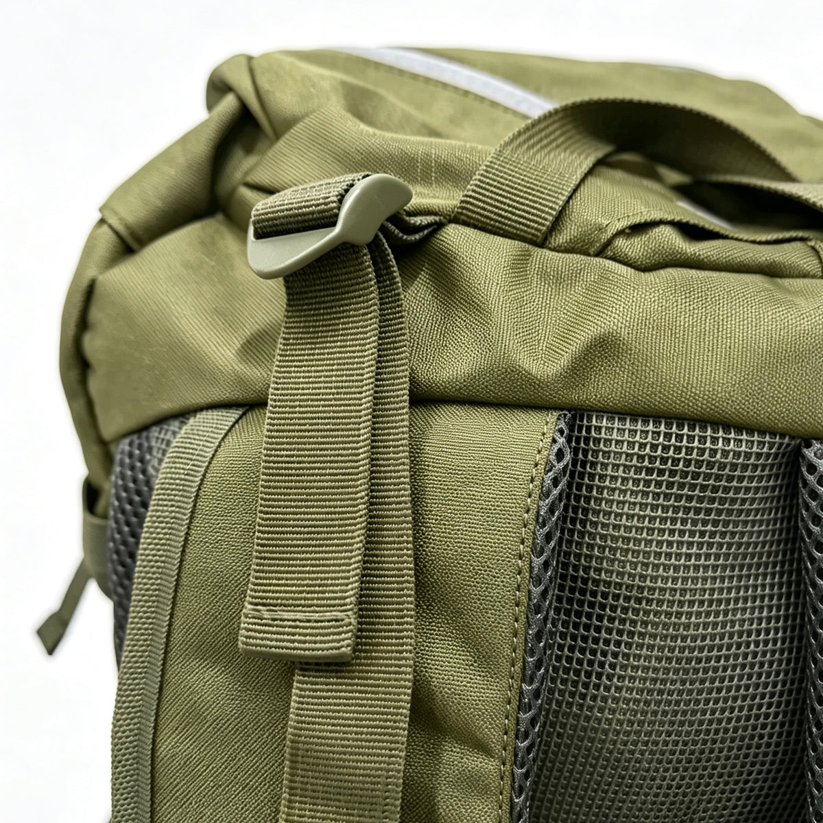 Close-up of an olive green tactical backpack showing the top flap, plastic buckle, webbing strap, and dark gray mesh ventilation pockets.