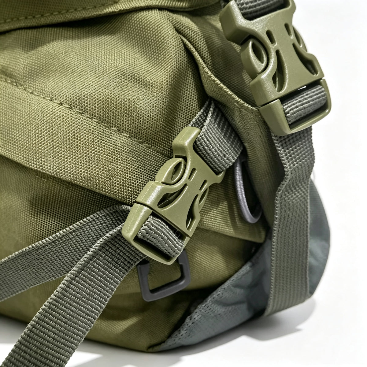 Close-up of an olive green nylon bag with matching olive green plastic buckle closures and gray webbing straps, photographed on a white background.