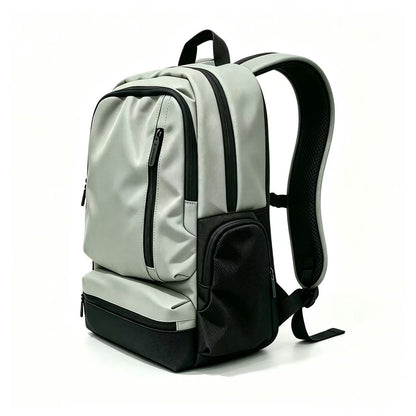 A light gray and black backpack shown from a three-quarter angle on a clean white background. The backpack features multiple zippered compartments, a padded shoulder strap, and a small white logo on the front pocket.