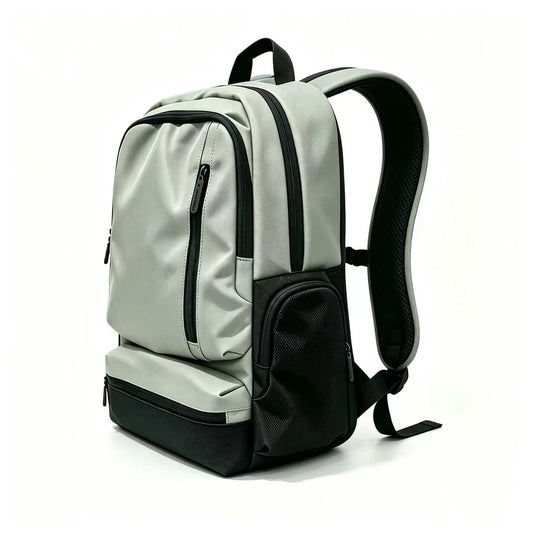 A light gray and black backpack shown from a three-quarter angle on a clean white background. The backpack features multiple zippered compartments, a padded shoulder strap, and a small white logo on the front pocket.